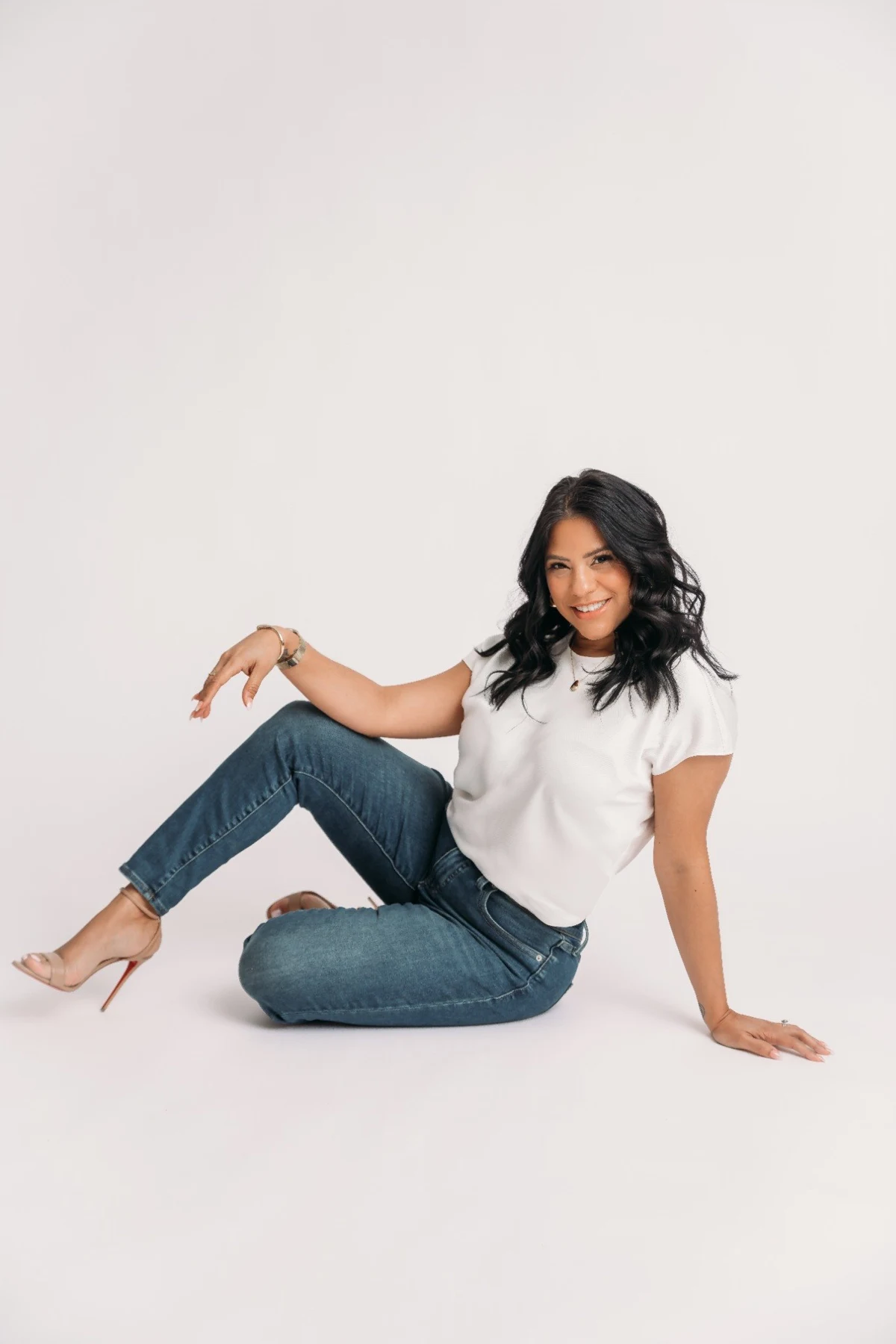 Shay in a white shirt and jeans seated on the studio floor